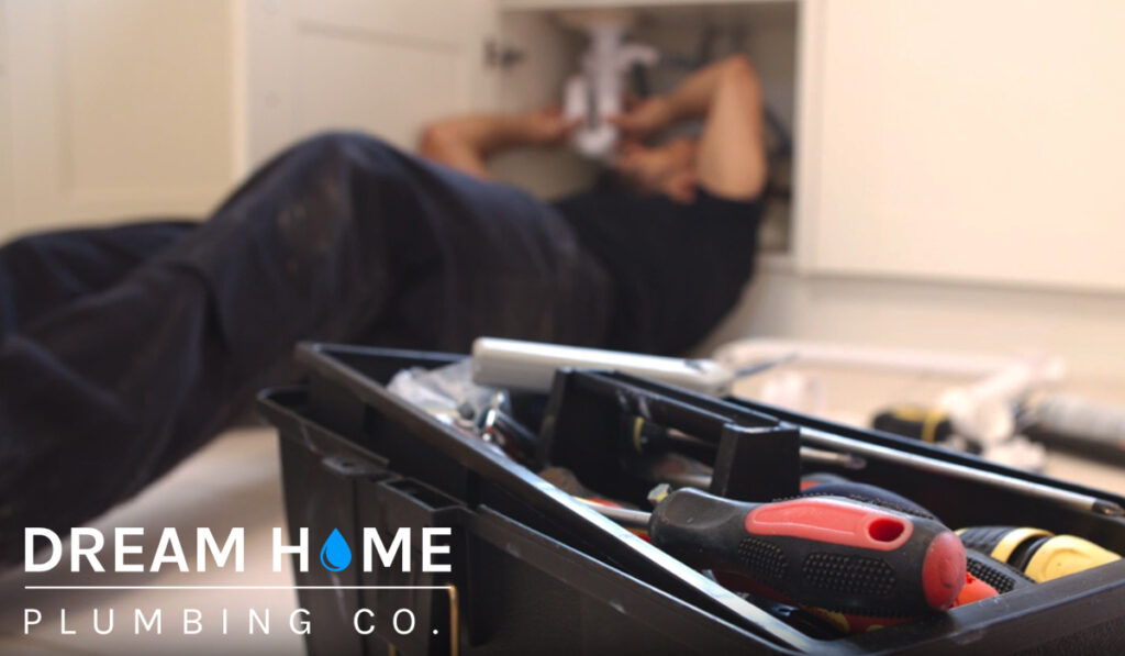 A man repairing the pipes under the sink. Plumbing services in Glen Ellyn for your home.